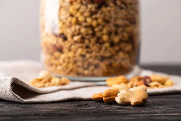 Blurred delicious granola in glass gar on napkin and nuts — Stock Photo