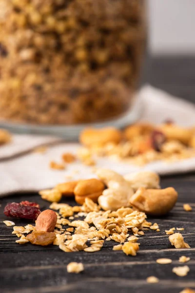 Blurred delicious granola in glass gar on napkin and nuts — Stock Photo