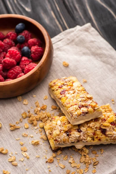 Deliziose barrette di muesli su tovagliolo con bacche sfocate — Foto stock