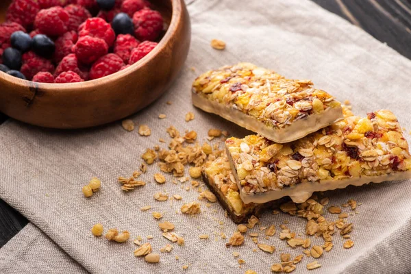 Deliziose barrette di muesli su tovagliolo con bacche sfocate — Foto stock