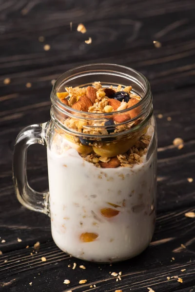 Delicious granola with yogurt, nuts, peach, blueberry in glass jar — Stock Photo