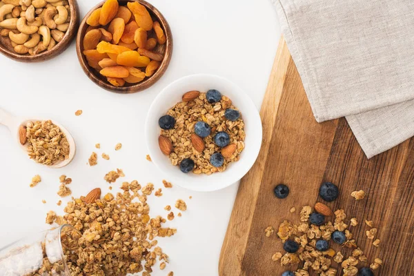 Vista superior de granola deliciosa com nozes, mirtilo e damascos secos isolados em branco — Fotografia de Stock