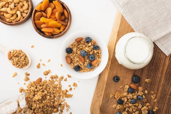 Top view of delicious granola with yogurt, nuts, blueberry and dried apricots isolated on white — Stock Photo