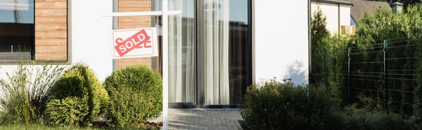 Fassade eines modernen Hauses in Rasennähe und Schild mit verkauftem Schriftzug, Banner — Stockfoto