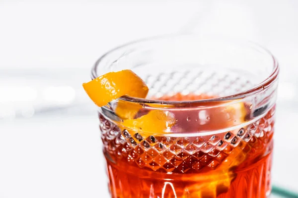 Close up of orange peel in glass with alcohol cocktail on white — Stock Photo