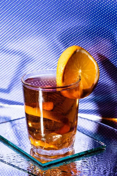 Vaso con cóctel mixto y naranja en rodajas de azul - foto de stock