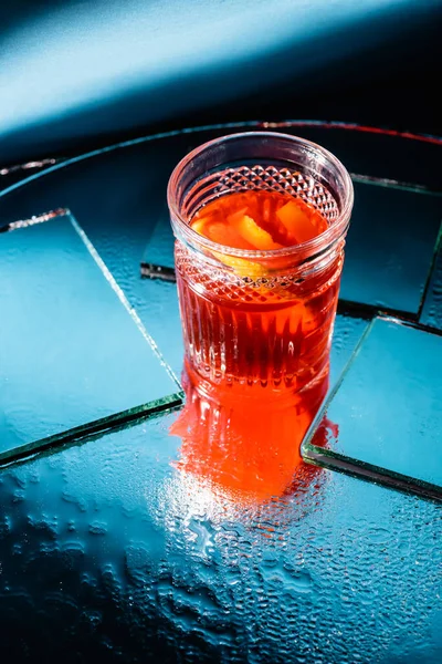 Gemixter Alkohol-Cocktail mit Whiskey in der Nähe von Spiegeln auf der Oberfläche und blauem Hintergrund — Stockfoto