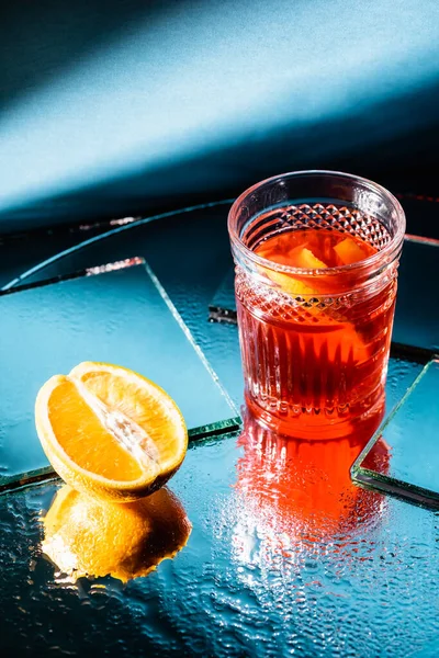 Mixed alcohol cocktail with rum near half of orange on blue — Stock Photo