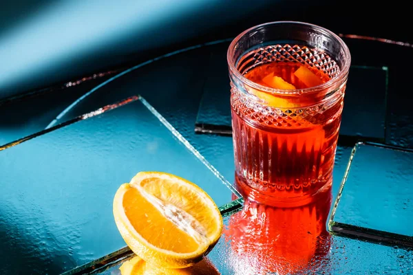 Cóctel de alcohol mezclado cerca de la mitad de naranja en azul - foto de stock