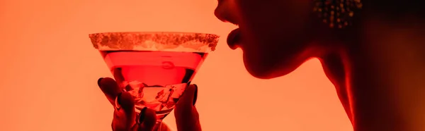 Cropped view of woman drinking margarita cocktail on orange, banner — Stock Photo