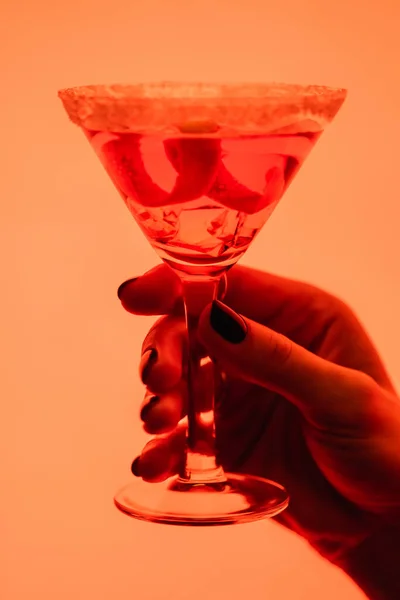 Close up of margarita cocktail with ice cubes in female hand on orange — Stock Photo