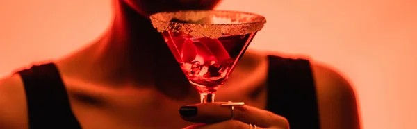 Margarita cocktail with ice cubes and salt in hand of woman on blurred orange background, banner — Stock Photo