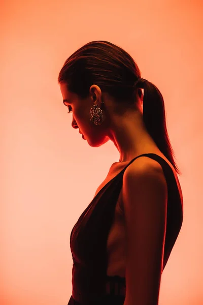 Profile of brunette young woman on orange background — Stock Photo