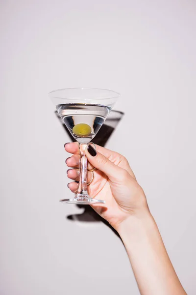 Cropped view of woman holding glass of martini with olive on white — Stock Photo