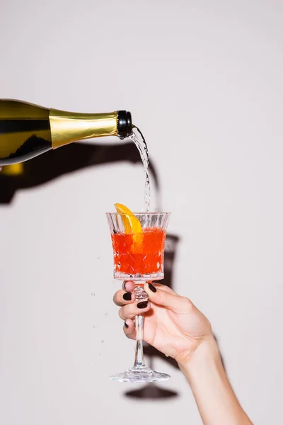 Champagne pouring in glass with cocktail from bottle near woman on white — Stock Photo