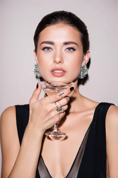 Morena mujer sosteniendo vaso de martini sobre blanco - foto de stock