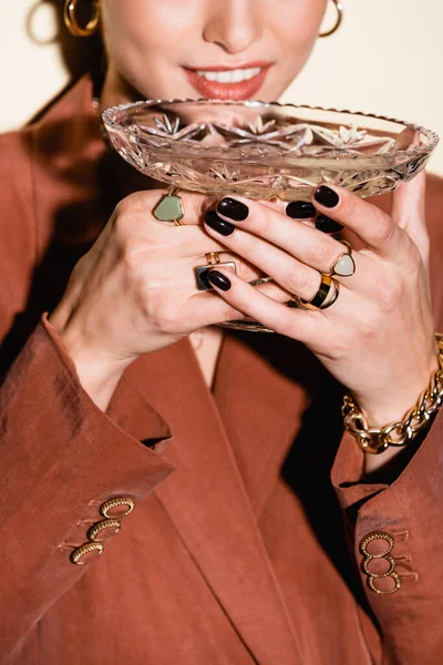 Обрезанный вид счастливой женщины в коричневом блейзере, пьющей шампанское из стекла на белом — стоковое фото