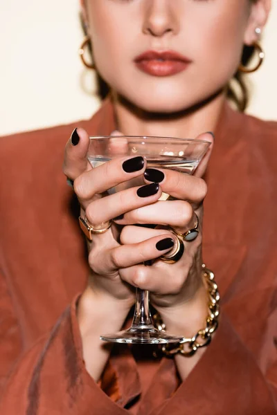 Glass of alcohol drink in hands of woman in blurred background — Stock Photo