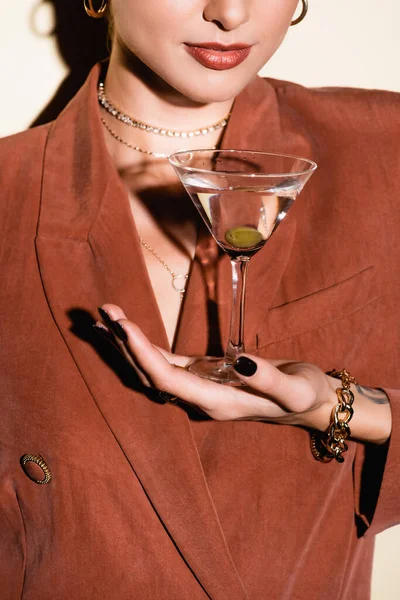 Vista recortada de mujer sosteniendo vaso de martini con oliva sobre blanco - foto de stock