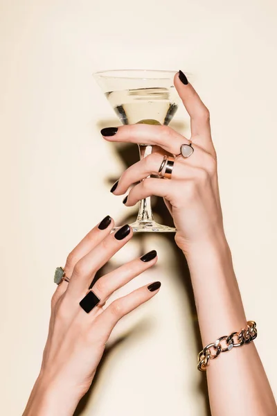 Vue recadrée de la femme avec des anneaux sur les doigts tenant verre de martini avec olive sur blanc — Photo de stock
