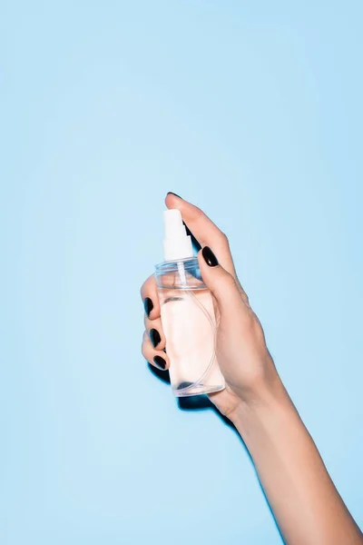 Vista cortada de mulher segurando higienizador de mão no azul — Fotografia de Stock