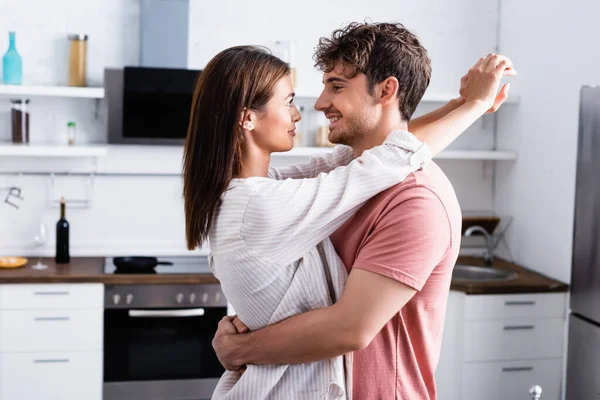 Sorrindo homem abraçando namorada na cozinha em casa — Fotografia de Stock