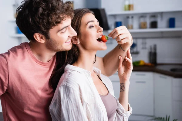 Sorrindo homem alimentando morena namorada com morango orgânico — Fotografia de Stock