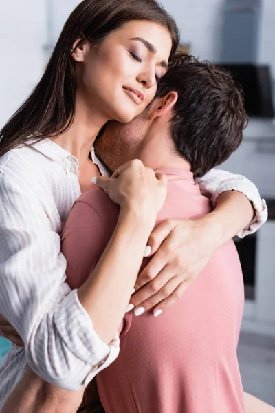 Jeune femme embrassant petit ami avec les yeux fermés à la maison — Photo de stock