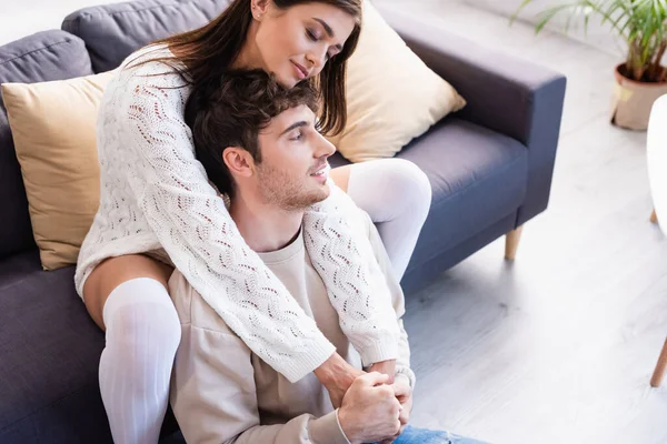 Sonriente hombre hoding manos de novia en calcetines de rodilla en el sofá en casa - foto de stock