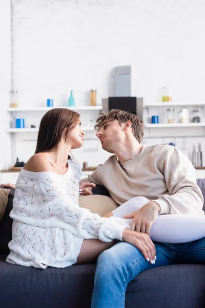 Young man touching legs of girlfriend in knee socks and knitted sweater in living room — Stock Photo