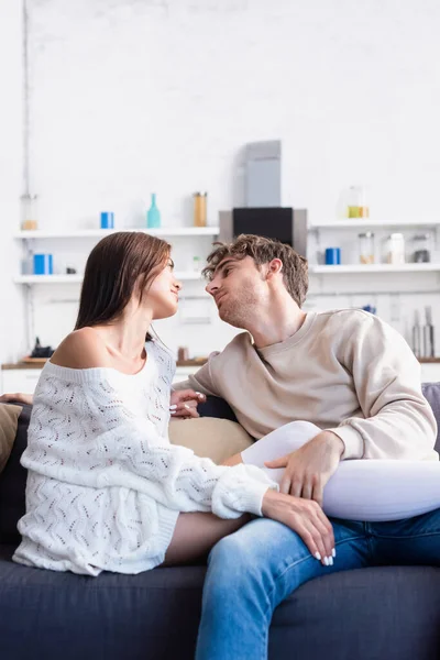 Jeune homme touchant les jambes de la petite amie en chaussettes de genou et pull tricoté dans le salon — Photo de stock