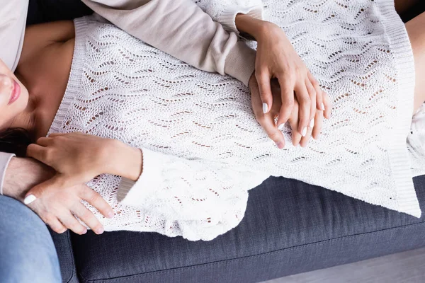 Vista dall'alto della donna in maglione lavorato a maglia che tocca le mani del fidanzato sul divano — Foto stock