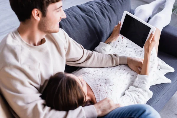 Digitales Tablet mit leerem Bildschirm in den Händen einer Frau neben lächelndem Freund auf verschwommenem Vordergrund — Stockfoto