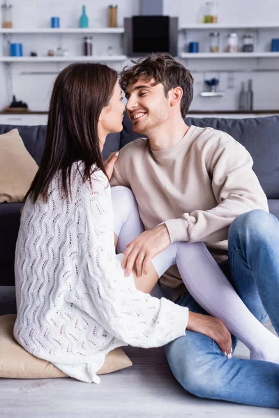 Homme souriant touchant petite amie dans des chaussettes de genou sur le sol — Photo de stock