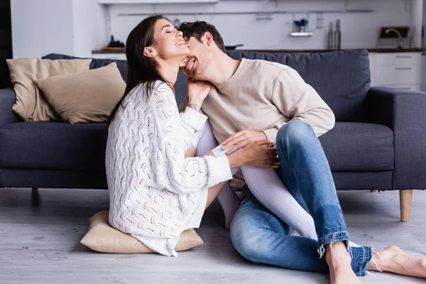 Cheerful woman in knee socks sitting near boyfriend on floor — Stock Photo