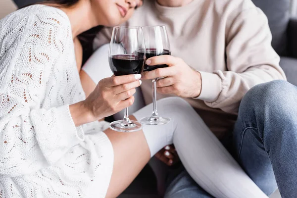 Cropped view of glasses of wine in hands of young coupe on blurred background — Stock Photo