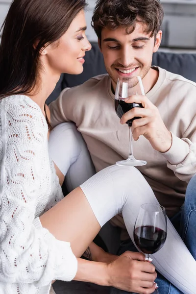 Smiling woman looking at boyfriend with glass of wine at home — Stock Photo