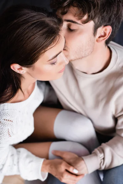 Vista aérea del hombre con los ojos cerrados besando novia en casa - foto de stock