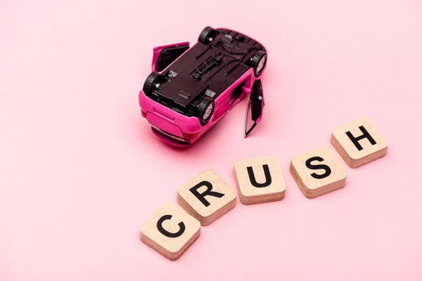 Toy car and word crush on cubes on pink background — Stock Photo