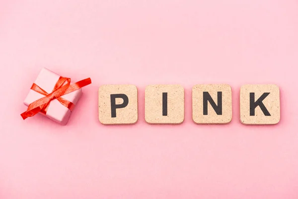 Vista superior de la palabra rosa en cubos y caja de regalo - foto de stock