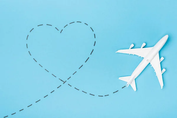 Top view of white plane model and heart on blue background — Stock Photo