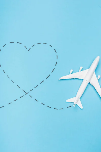 Top view of white plane model and heart on blue background — Stock Photo