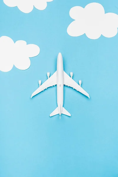 Top view of white plane model on blue background with white clouds — Stock Photo