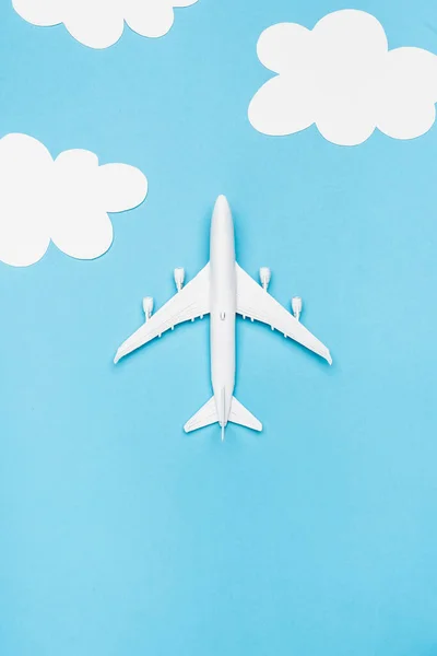 Top view of white plane model on blue background with white clouds — Stock Photo