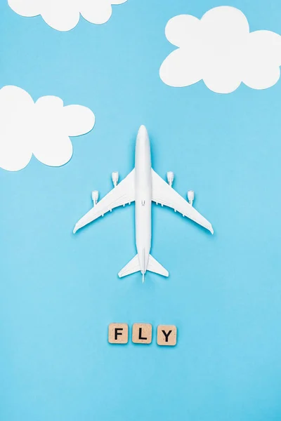 Top view of plane model and cubes with word fly on blue sky background — Stock Photo