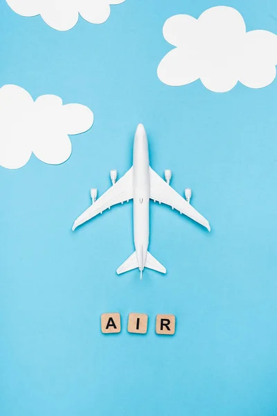 Top view of plane model and cubes with word air on blue sky background — Stock Photo