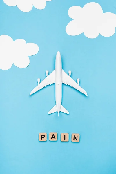 Top view of plane model and cubes with word pain on blue sky background — Stock Photo