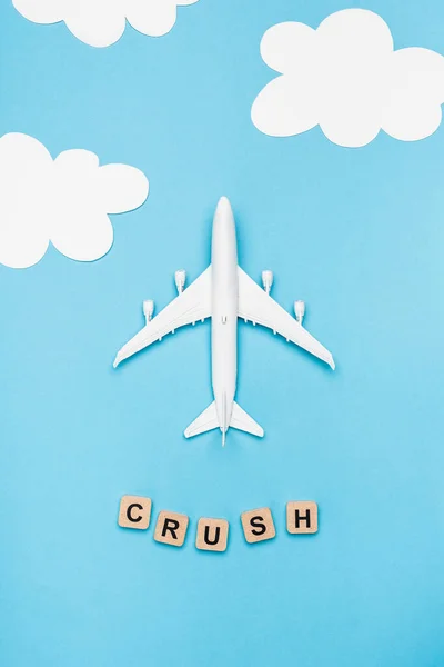 Top view of plane model and cubes with word crush on blue sky background — Stock Photo