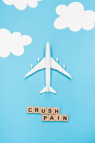 Draufsicht auf Flugzeugmodell und Würfel mit Wortquetschschmerzen auf blauem Himmelshintergrund — Stockfoto