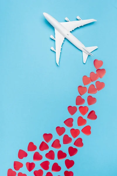 Top view of plane model and red hearts on blue background — Stock Photo